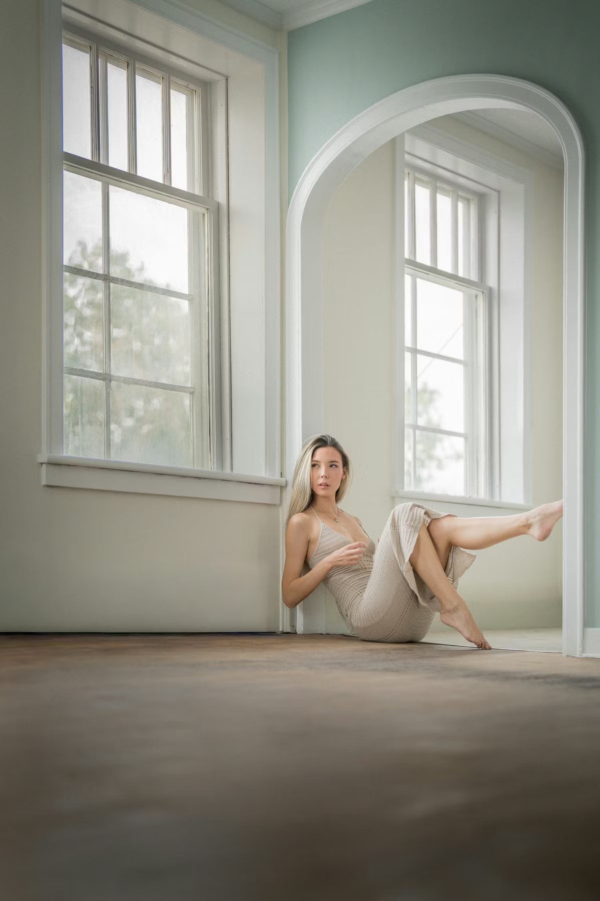 Soft natural-light portrait of a woman by an arched window